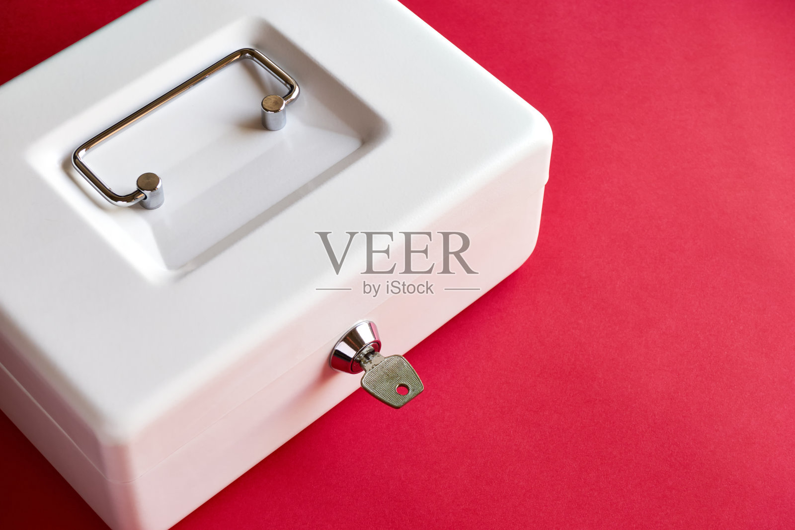 关闭的现金箱与钥匙锁在粉红色的背景照片摄影图片