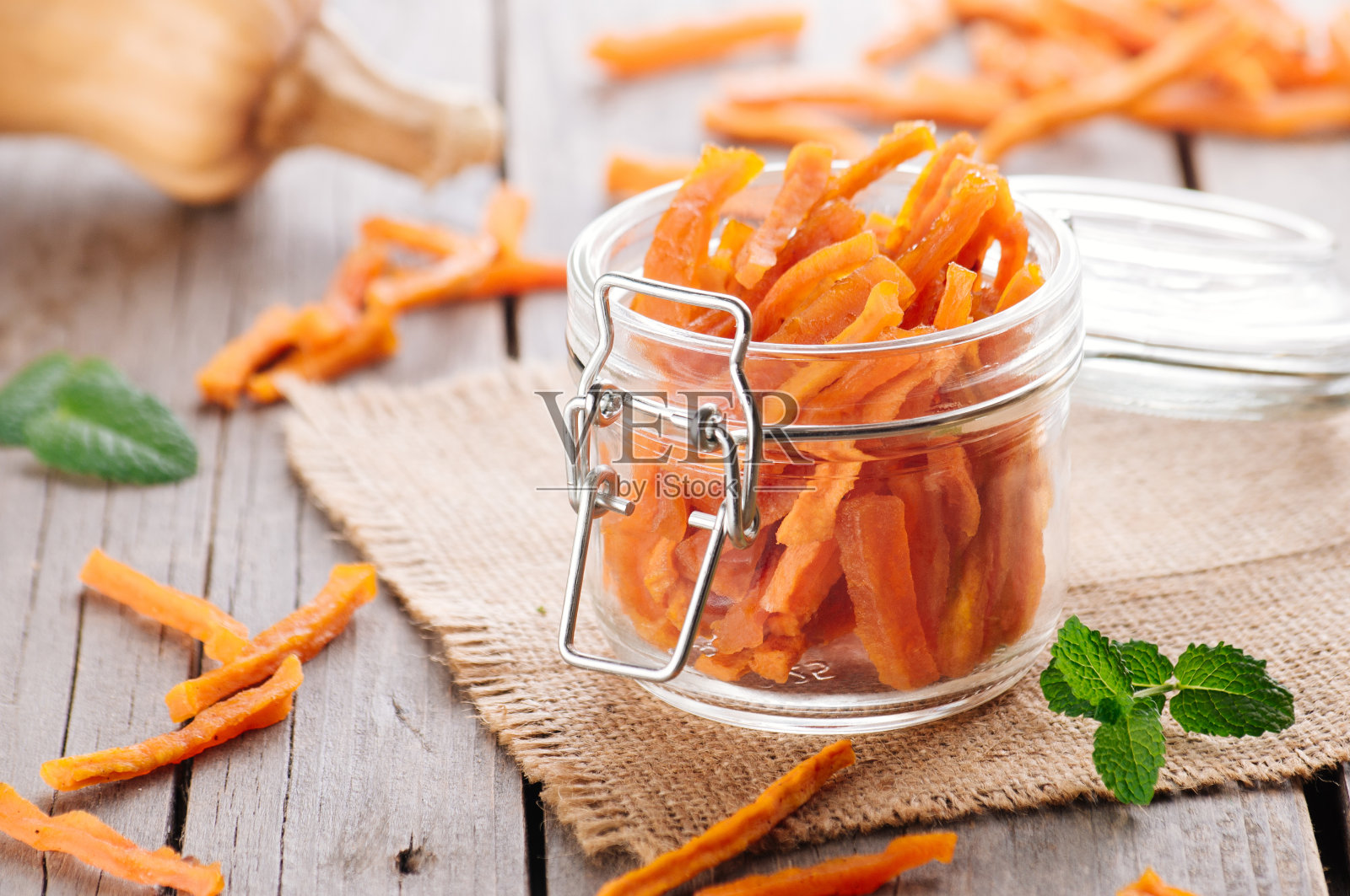 自制的蜜饯南瓜片放在玻璃罐里，背景是质朴的木头照片摄影图片