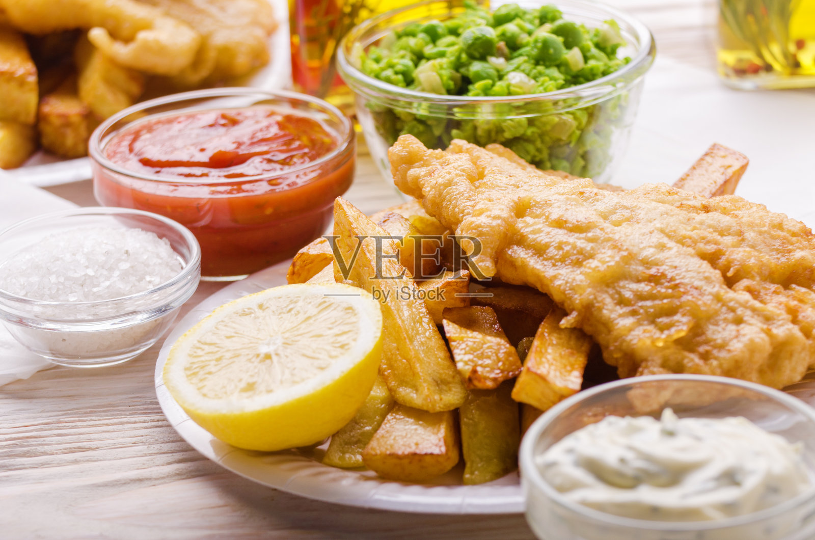 传统的英国街头小吃鱼和薯条，配上番茄酱和塔塔酱，还有豌豆糊放在纸盘子里照片摄影图片