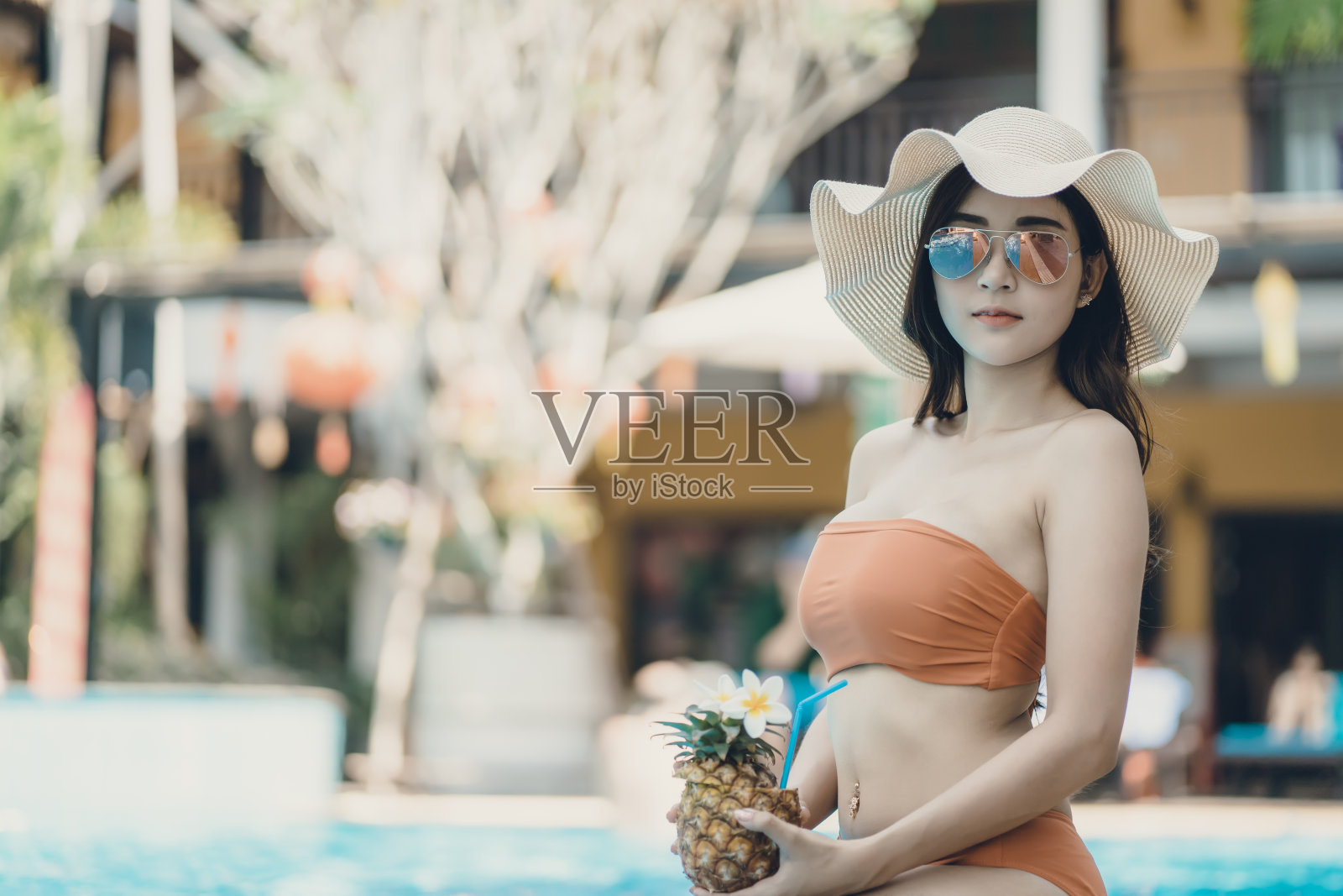 美丽的亚洲女人穿着比基尼在游泳池享受暑假。照片摄影图片