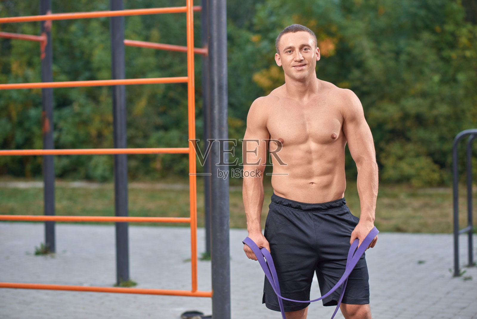 有吸引力的男人摆姿势在锻炼与阻力带。照片摄影图片