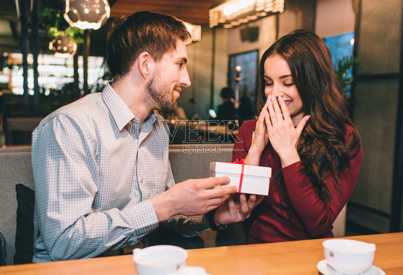 那家伙正在给他的女朋友一个装在白色盒子里的礼物。她没想到会这样。他喜欢让心爱的女人开心。照片摄影图片