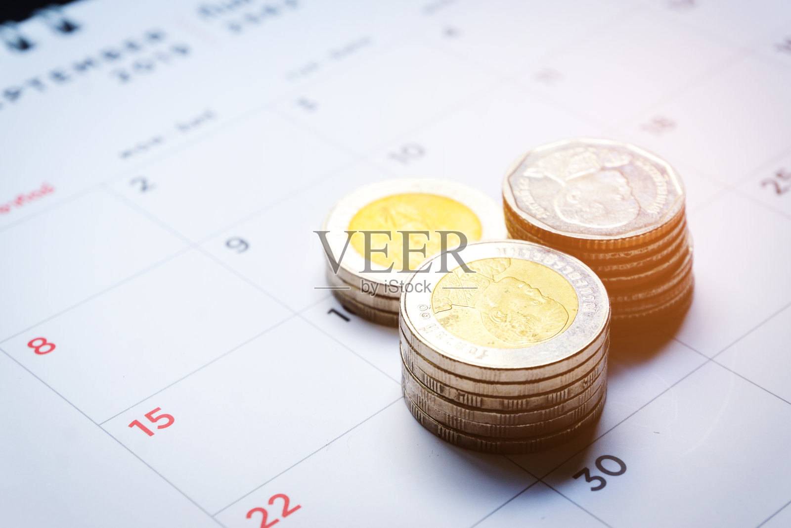 特写的泰铢钱堆在印刷日历与数字在黑色和红色的背景。储蓄、商业和金融的概念。照片摄影图片