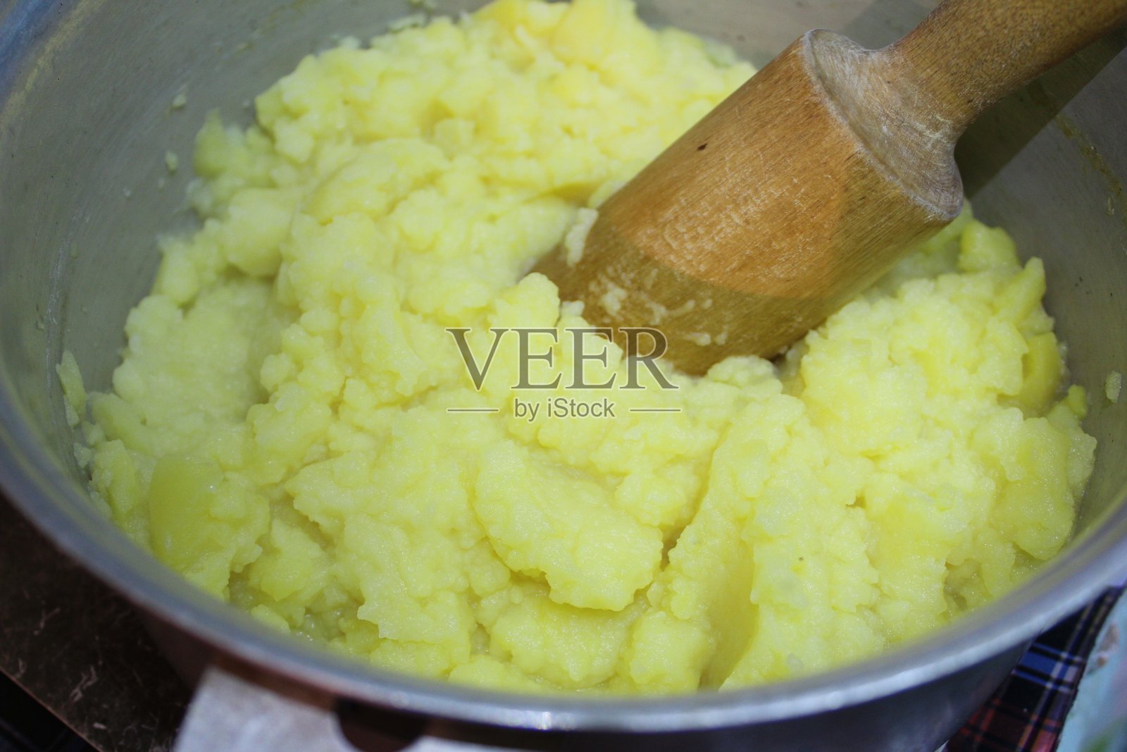 用木杵在平底锅里煮土豆泥照片摄影图片
