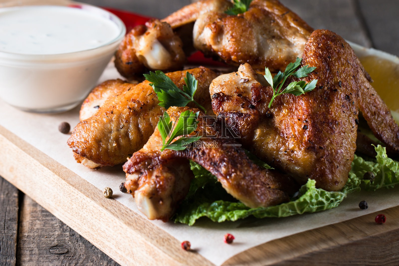 烧烤鸡翅与薯条和啤酒的特写照片。烤肉配酱汁，番茄酱，蛋黄酱。快餐和垃圾食品的概念。照片摄影图片