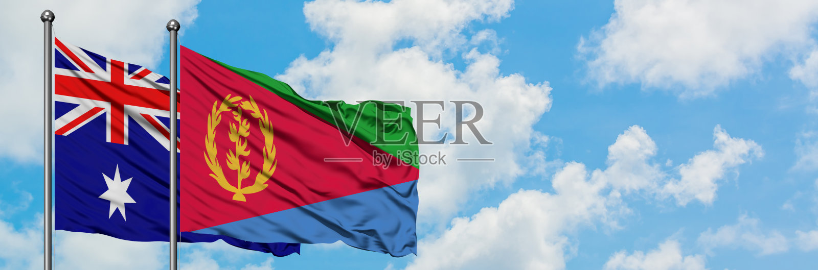澳大利亚和厄立特里亚的国旗迎风飘扬，对抗着白色多云的蓝天。外交理念，国际关系。照片摄影图片