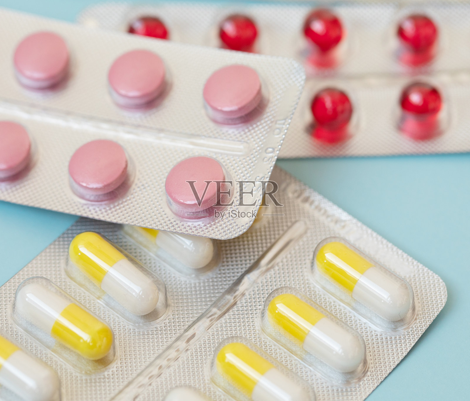 彩色抗菌药丸，蓝色背景。照片摄影图片