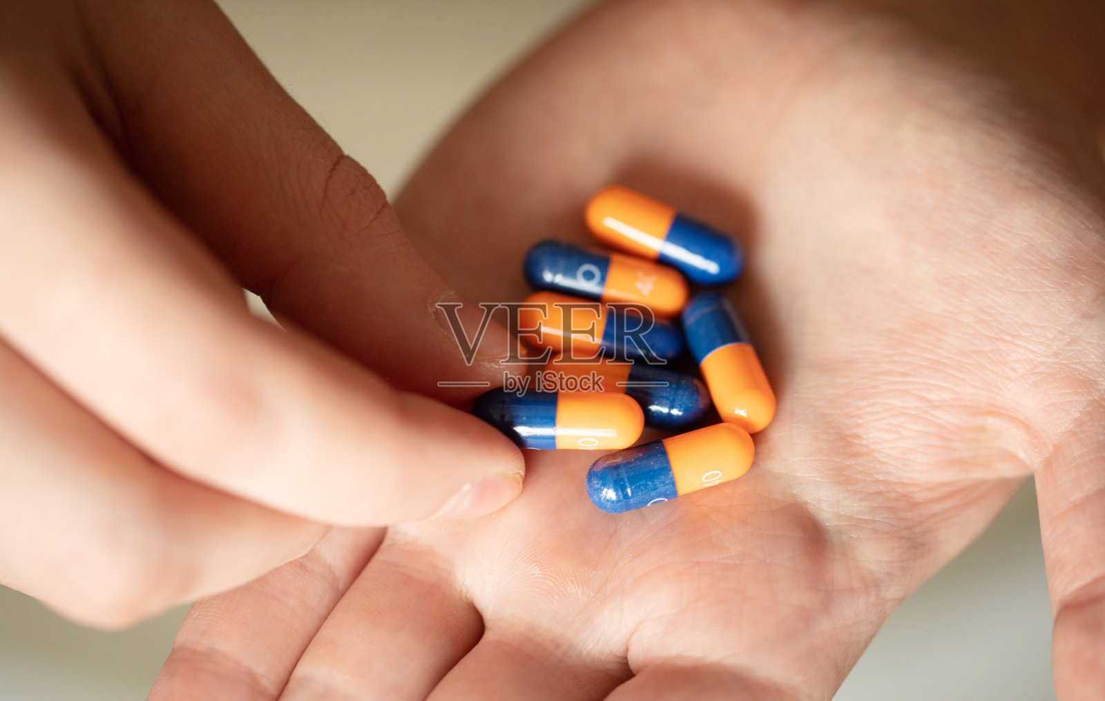 在蓝色背景上手持彩色药丸的特写镜头。照片摄影图片