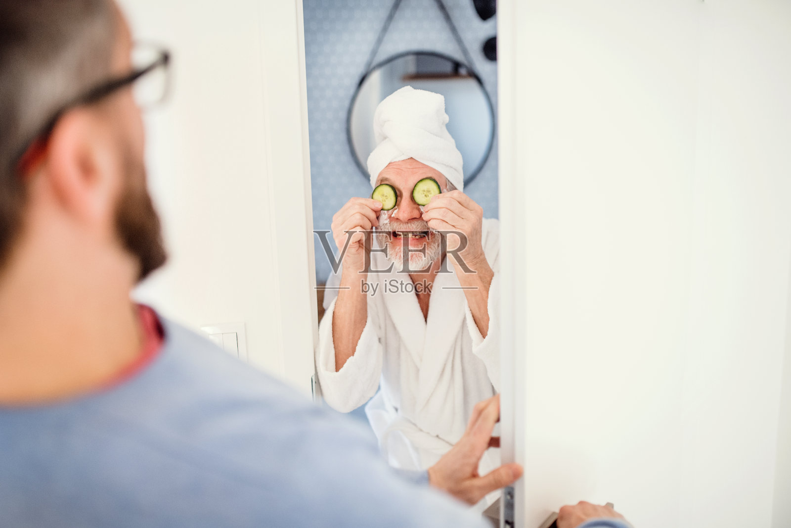 一个成年潮人的儿子和年长的父亲在室内浴室里玩。照片摄影图片