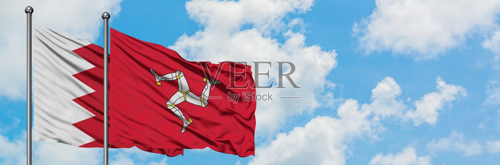 巴林和马恩岛国旗在白色多云蓝天下飘扬，外交概念，国际关系照片摄影图片