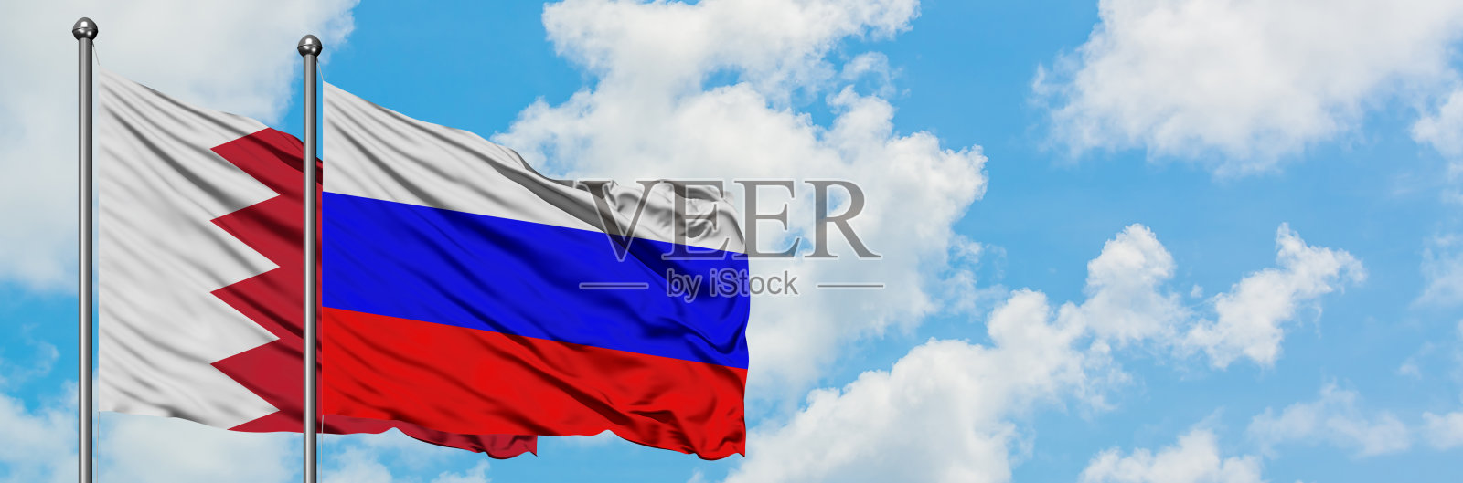 巴林和俄罗斯国旗在白色多云蓝天下飘扬，外交概念和国际关系照片摄影图片