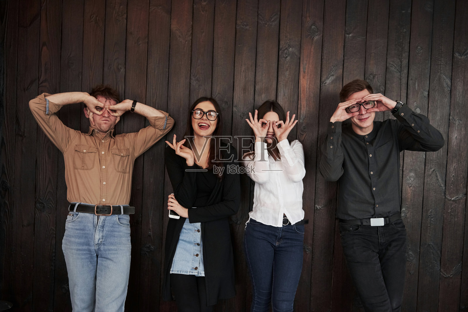 你无聊的时候就会这么做。青年靠着黑色的木墙站着。一群朋友聚在一起照片摄影图片