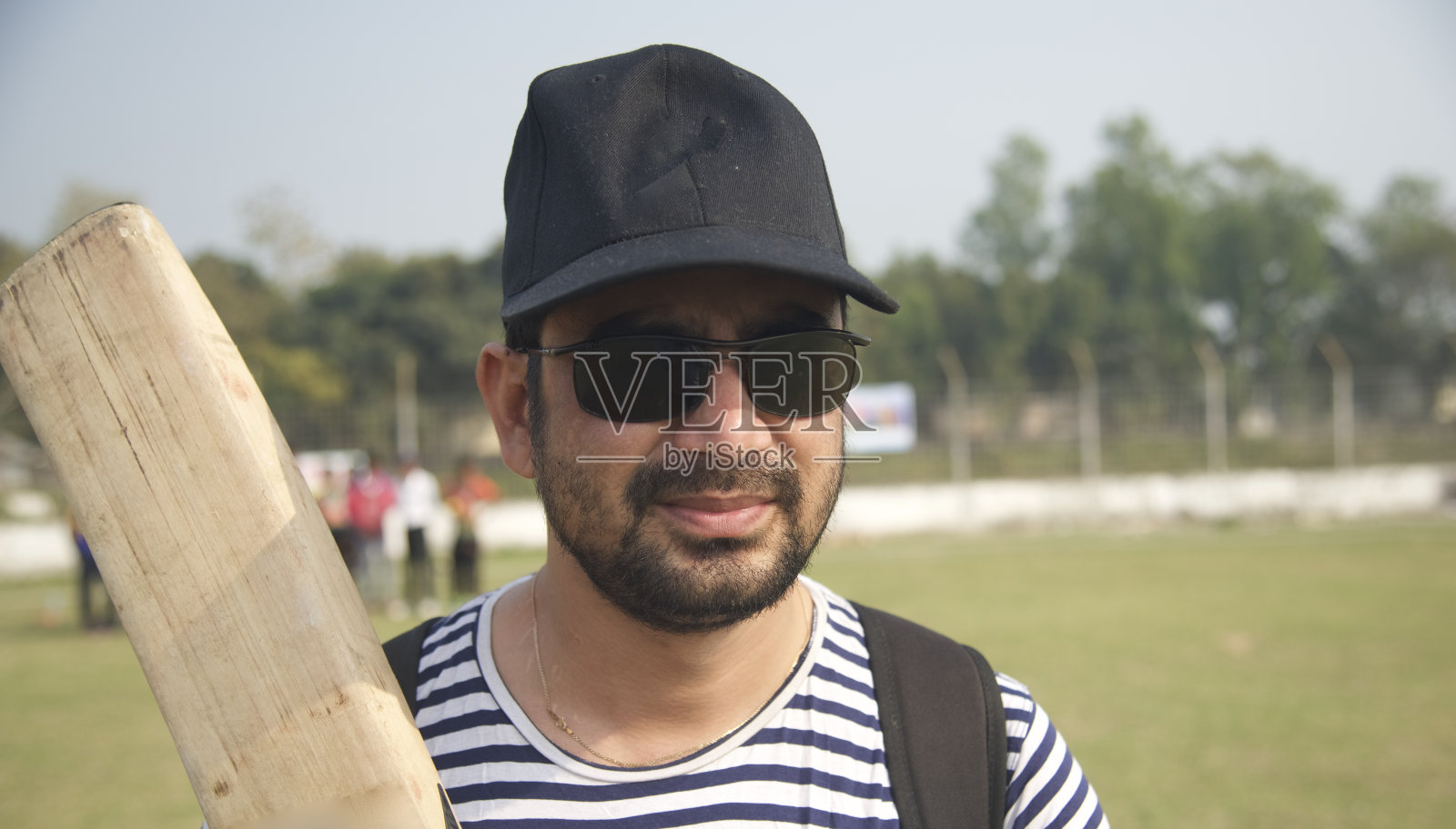 一个拿着板球棒的人站在地上照片摄影图片