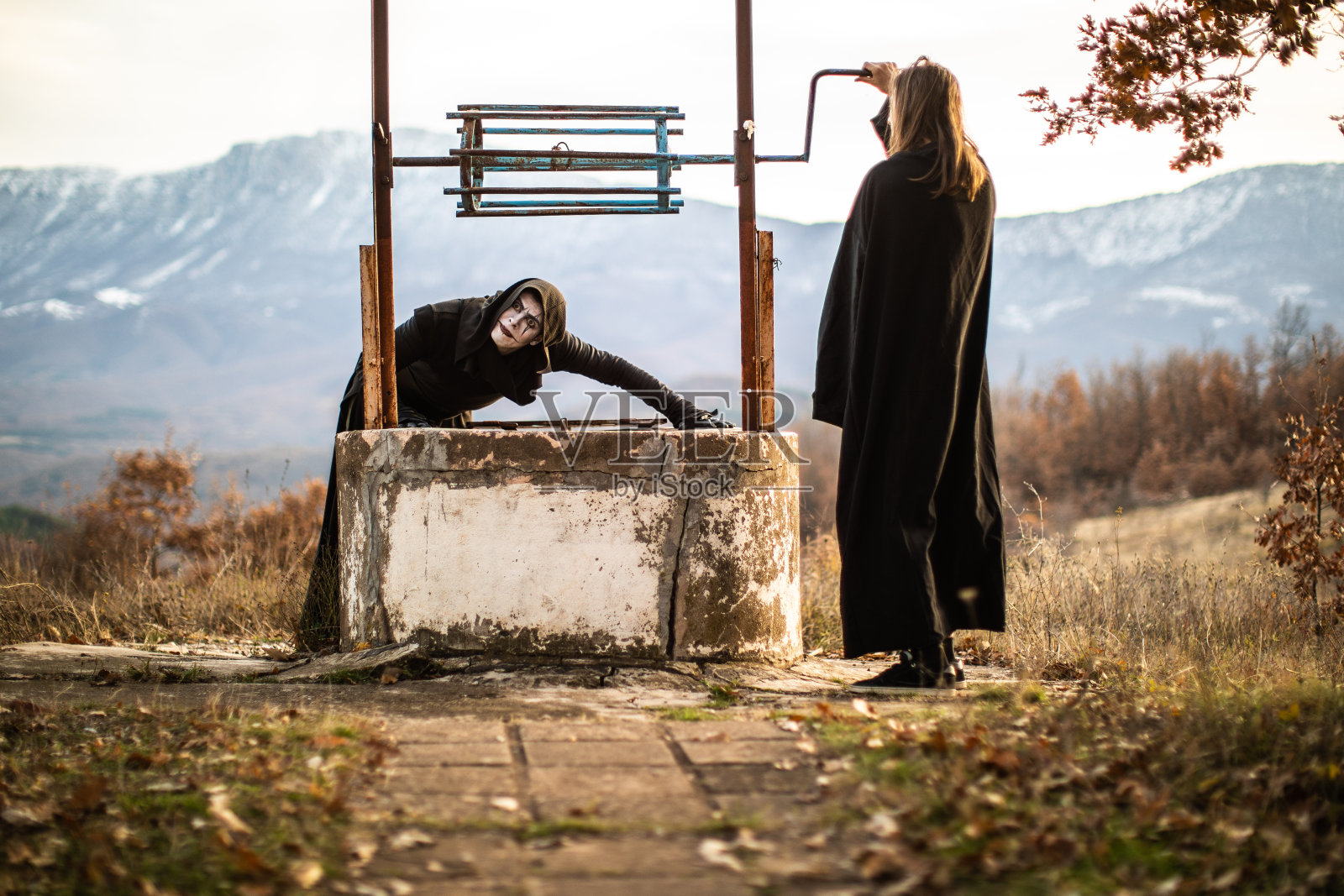 穿着黑衣的奇怪男人站在井边照片摄影图片