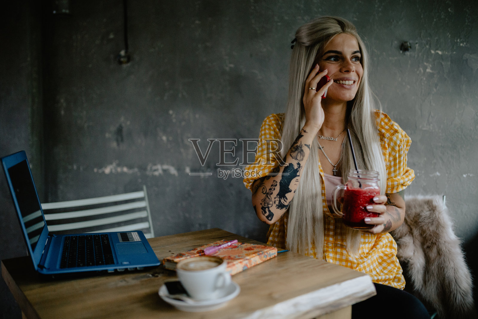 女人喝冰沙，用手机和笔记本电脑照片摄影图片