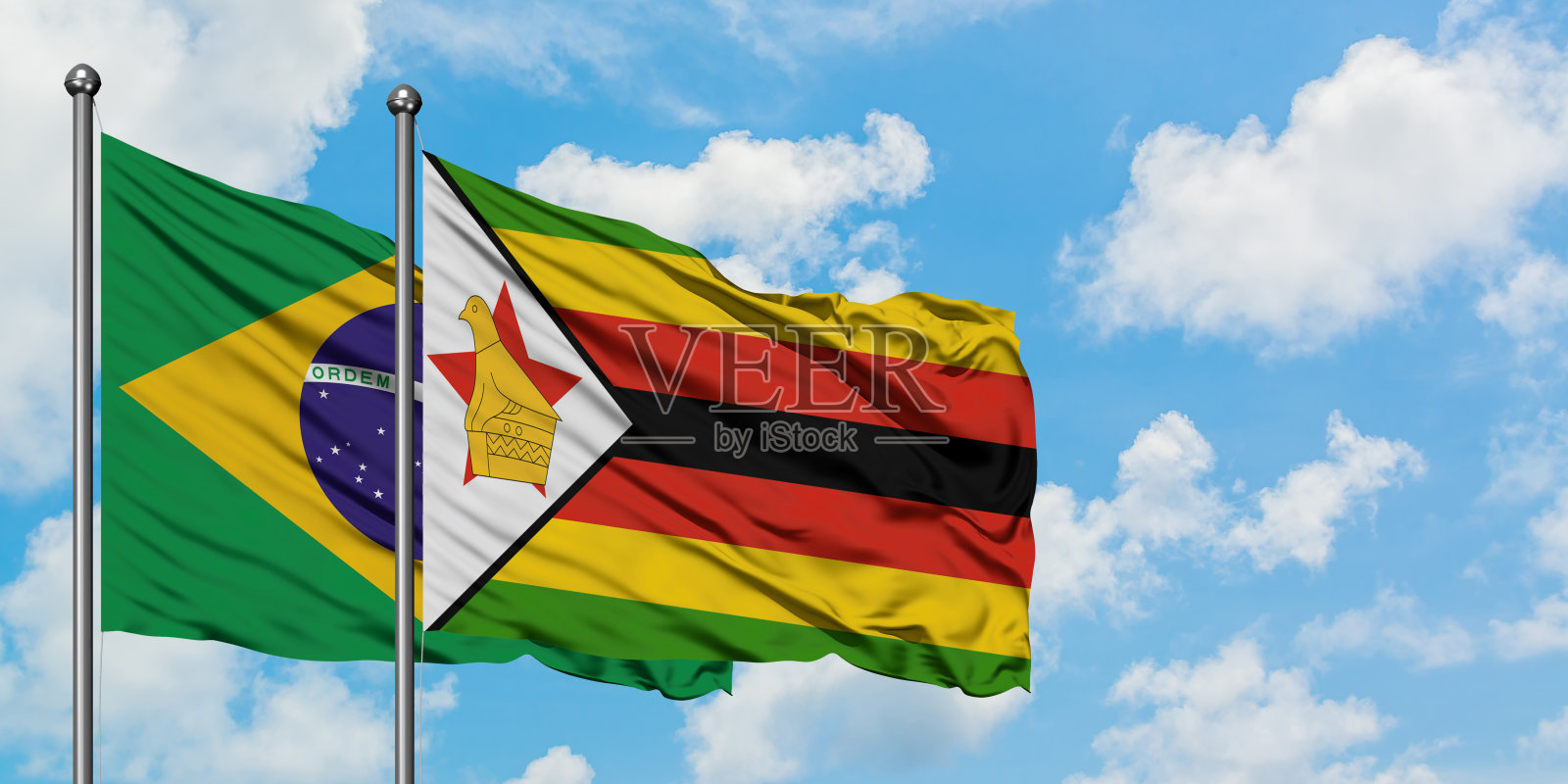 巴西和津巴布韦的国旗在风中飘扬，对抗着白色多云的蓝天。外交理念，国际关系。照片摄影图片