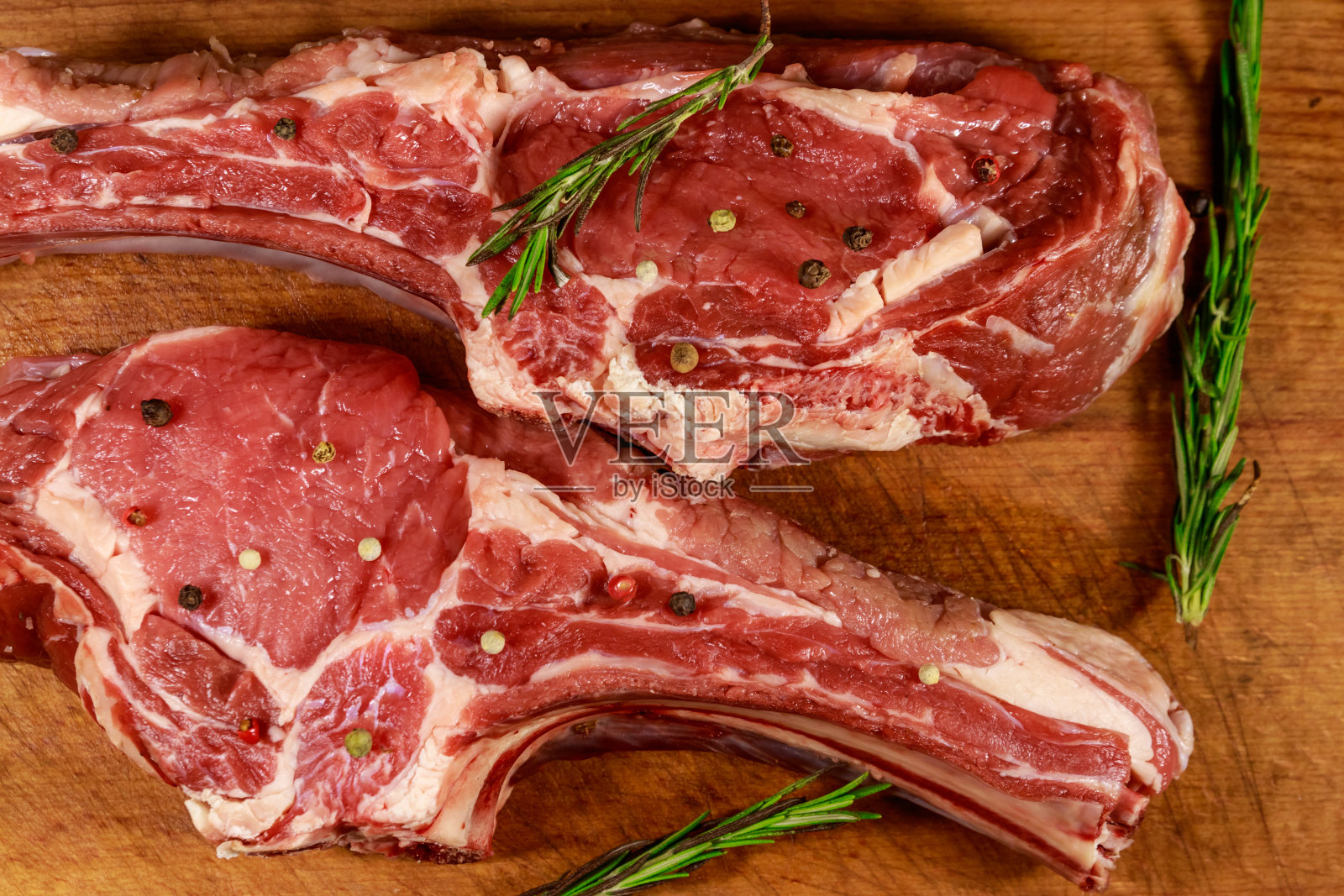 新鲜生牛眼牛排骨配香料和迷迭香放在木桌上。俯视图照片摄影图片