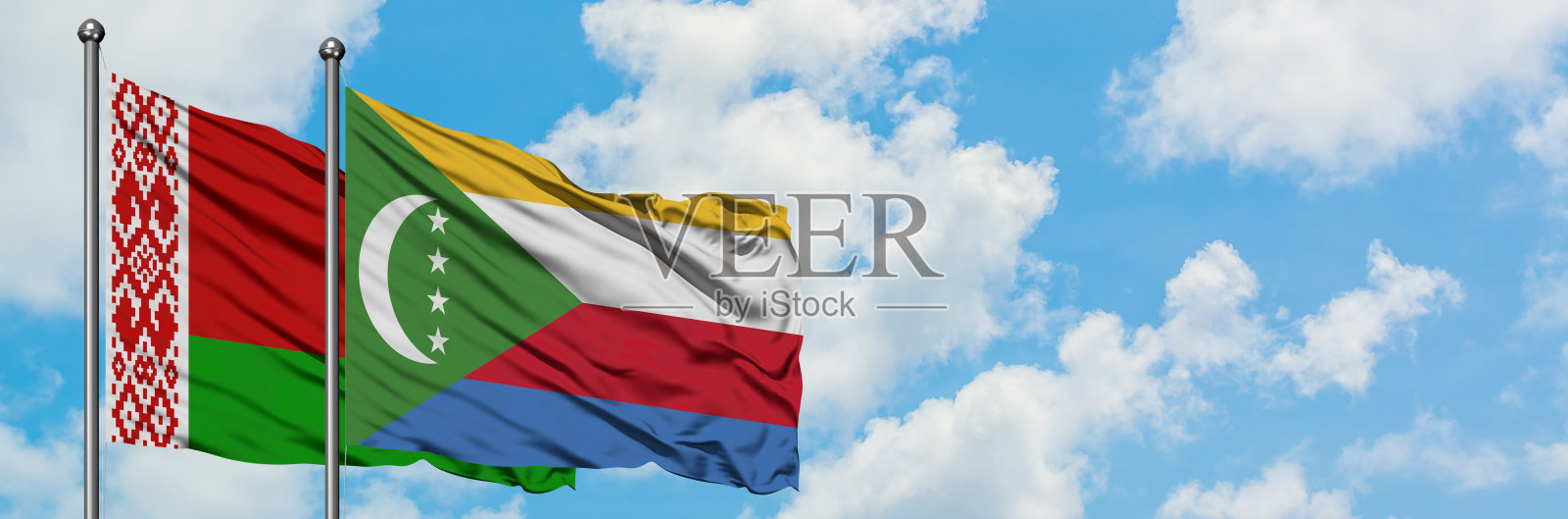 白俄罗斯和科摩罗的国旗迎风飘扬，对抗着白色多云的蓝天。外交理念，国际关系。照片摄影图片