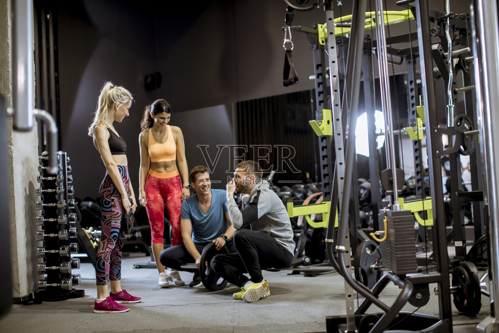 健身后，穿着运动服的朋友们坐在健身房的地板上有说有笑照片摄影图片