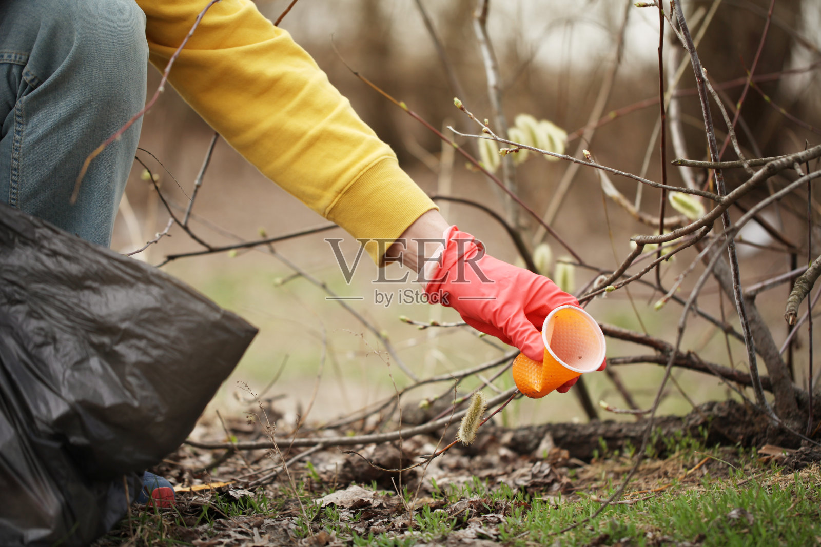 志愿者的手从垃圾地上举起。大自然的春季大扫除，户外的垃圾和垃圾照片摄影图片