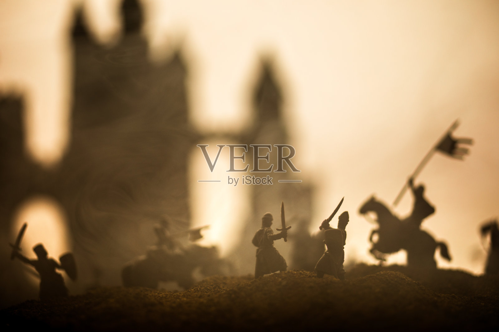有骑兵和步兵的中世纪战斗场景。剪影的人物作为单独的对象，战斗之间的战士在日落雾蒙蒙的背景。照片摄影图片