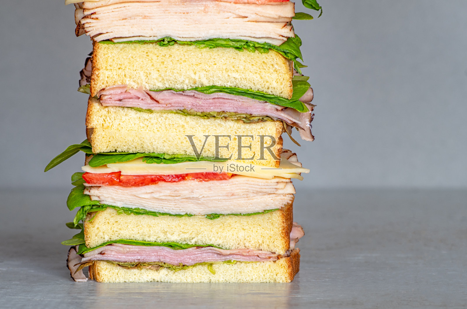 新鲜的熟食风格三明治与生菜，几种不同的蔬菜，西红柿，奶酪，肉类类似的火腿，鸡肉或火鸡。适合打印菜单，在线食物订购，食品营销活动或海报。照片摄影图片