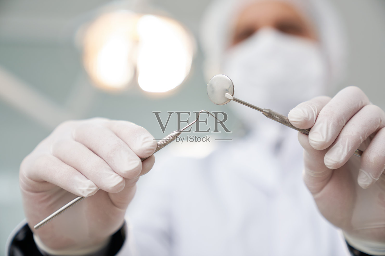 牙医戴着医用帽和面罩看着病人。照片摄影图片