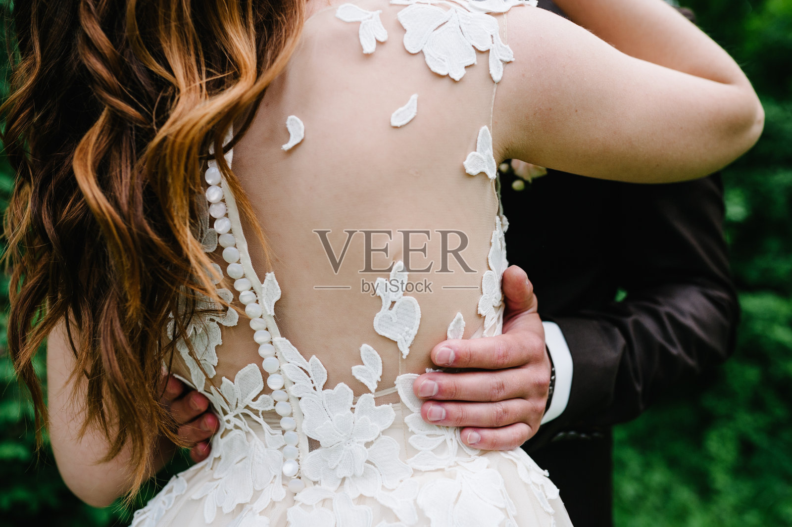 后面的后视图。婚礼夫妇拥抱在公园的背景自然，户外。新郎新娘拥抱。婚礼仪式。照片摄影图片