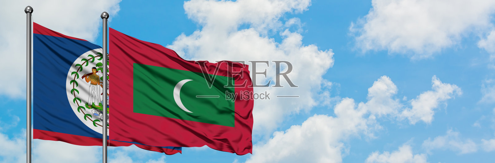 伯利兹和马尔代夫的国旗在风中飘扬，对抗着白色多云的蓝天。外交理念，国际关系。照片摄影图片
