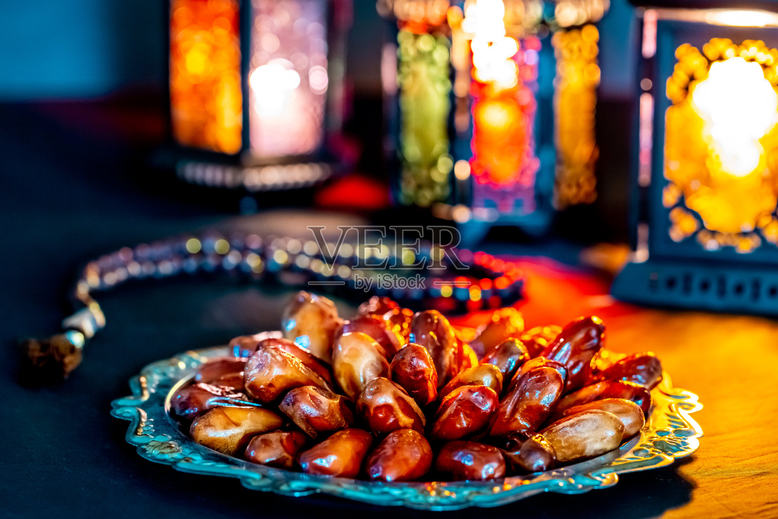 斋月圣月穆斯林盛宴，深色背景下托盘上的椰枣与闪亮的回教斋月灯笼照片摄影图片