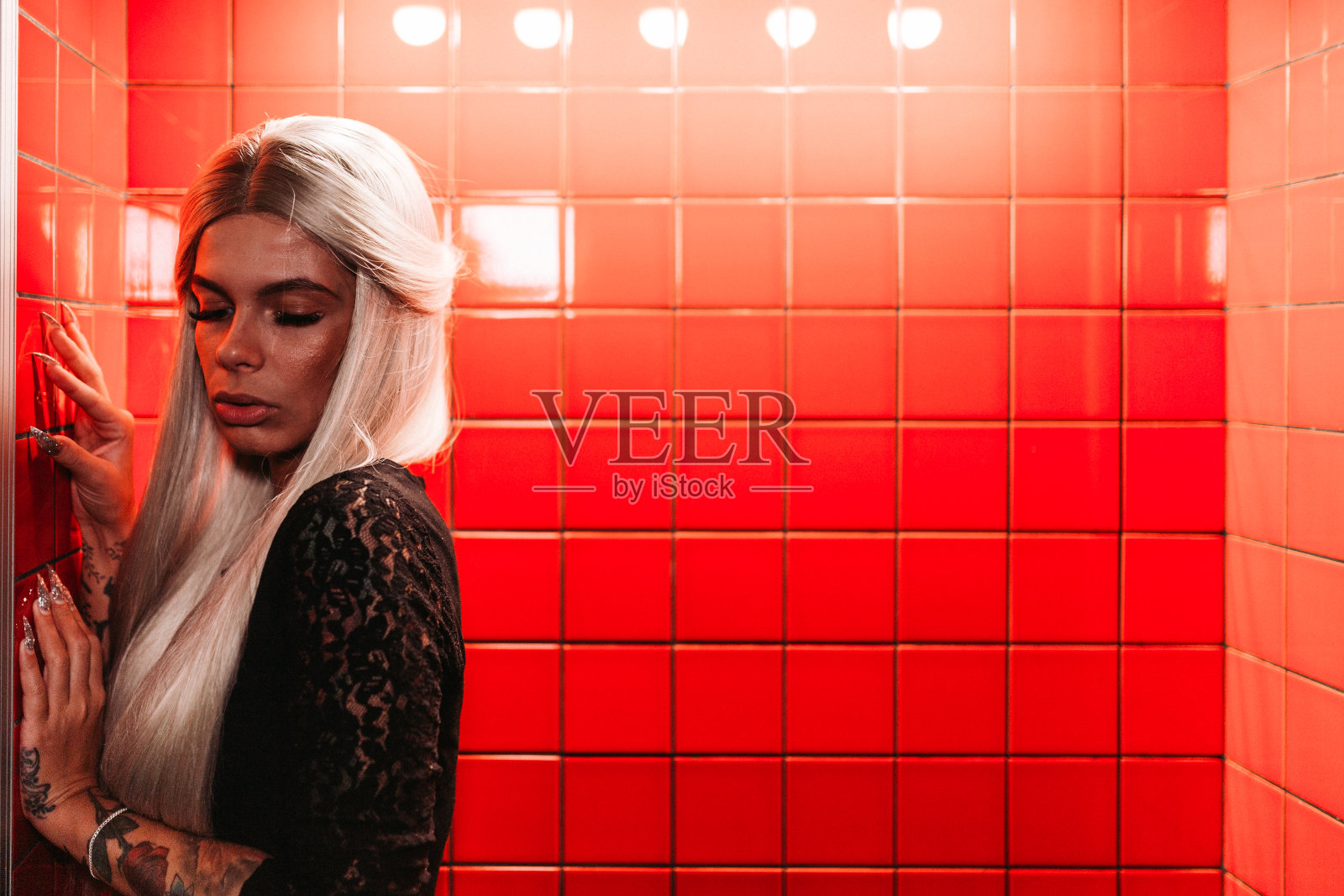 年轻的金发女人，背景是红瓷砖照片摄影图片