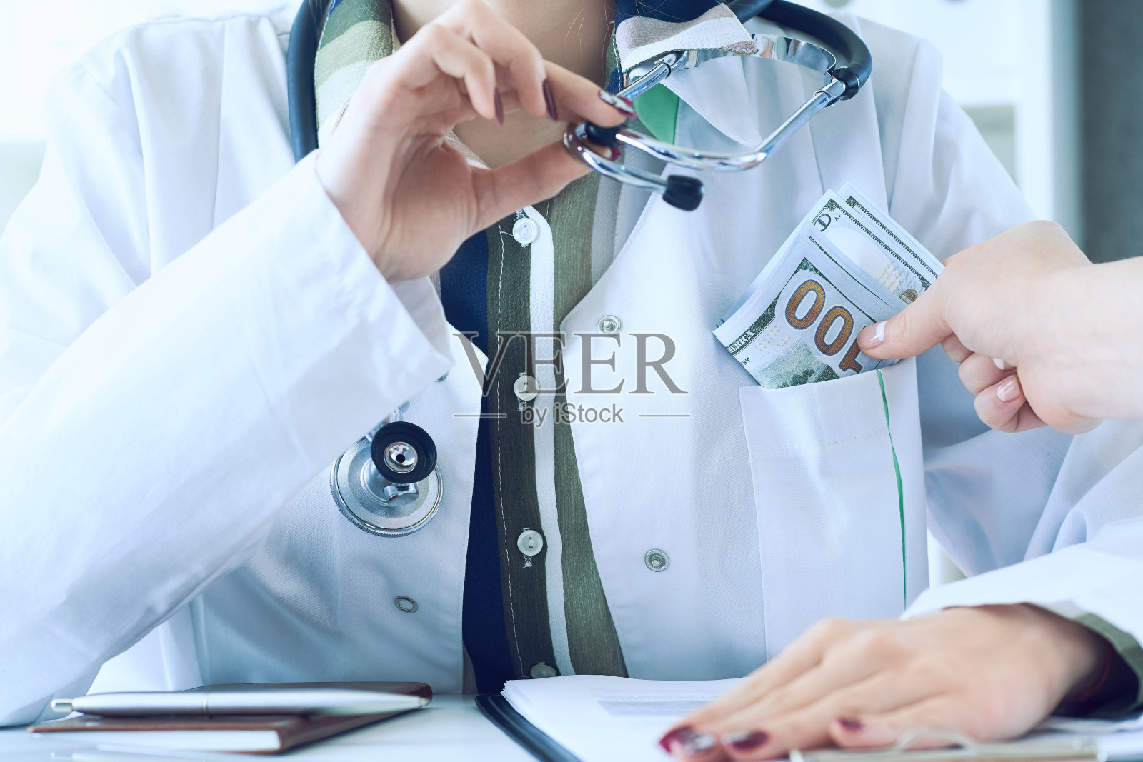 医生收受巨额美元钞票作为贿赂。医疗保健行业概念中的腐败。照片摄影图片