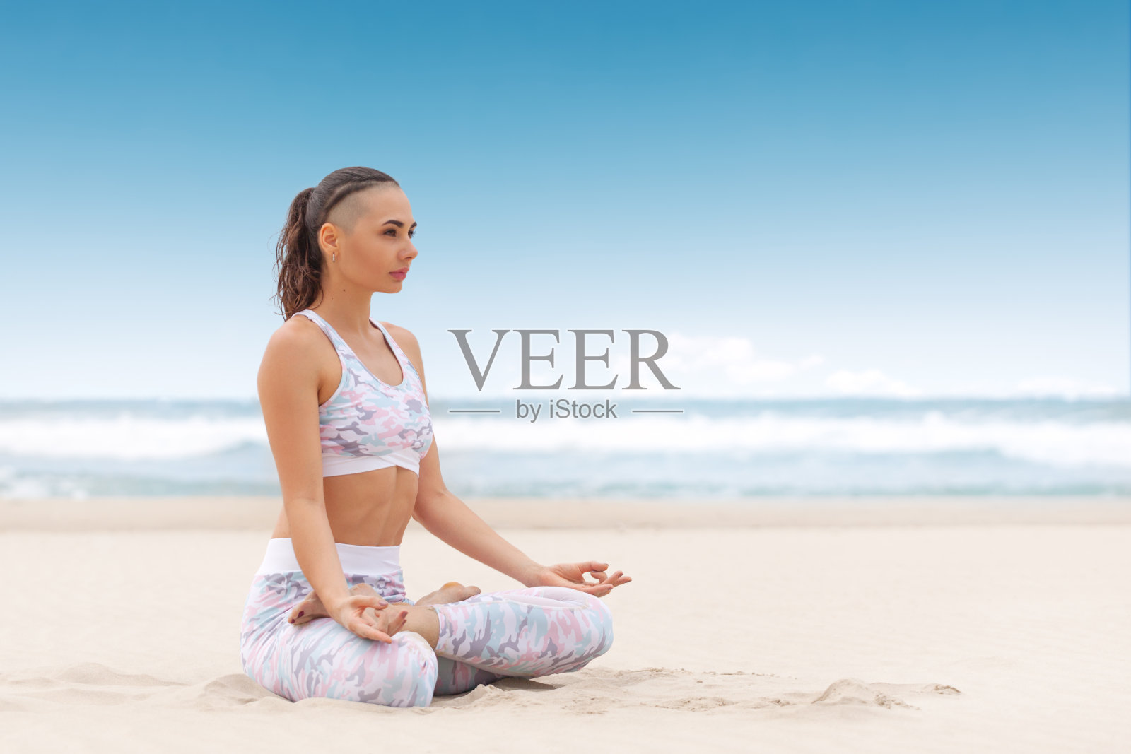 年轻美丽的女人放松在瑜伽莲花位置上的海沙照片摄影图片