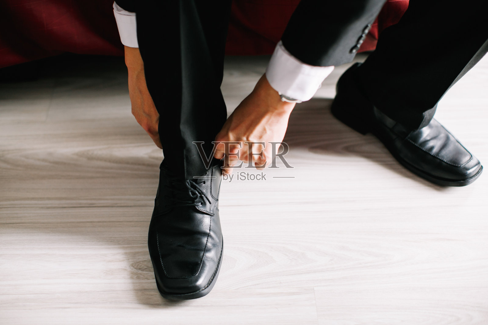 新郎正在系着一只黑皮鞋的鞋带照片摄影图片