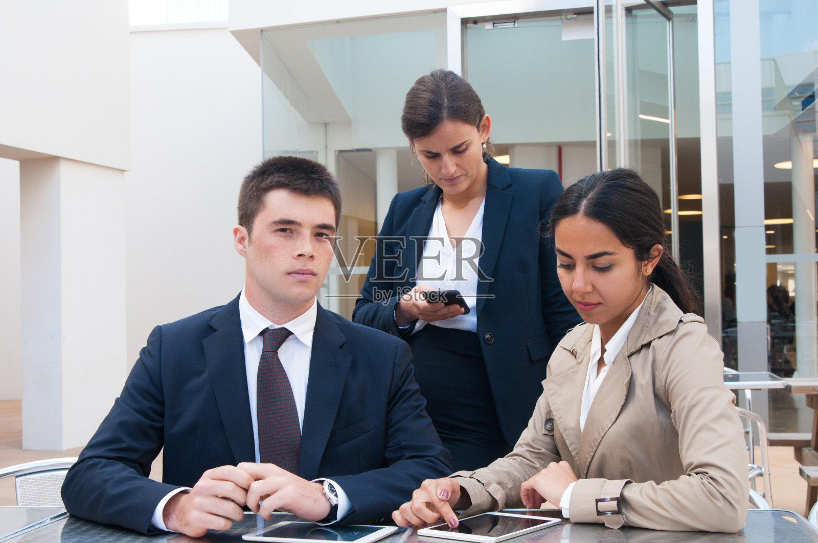 严肃的商务人士在户外办公桌上使用电子产品照片摄影图片