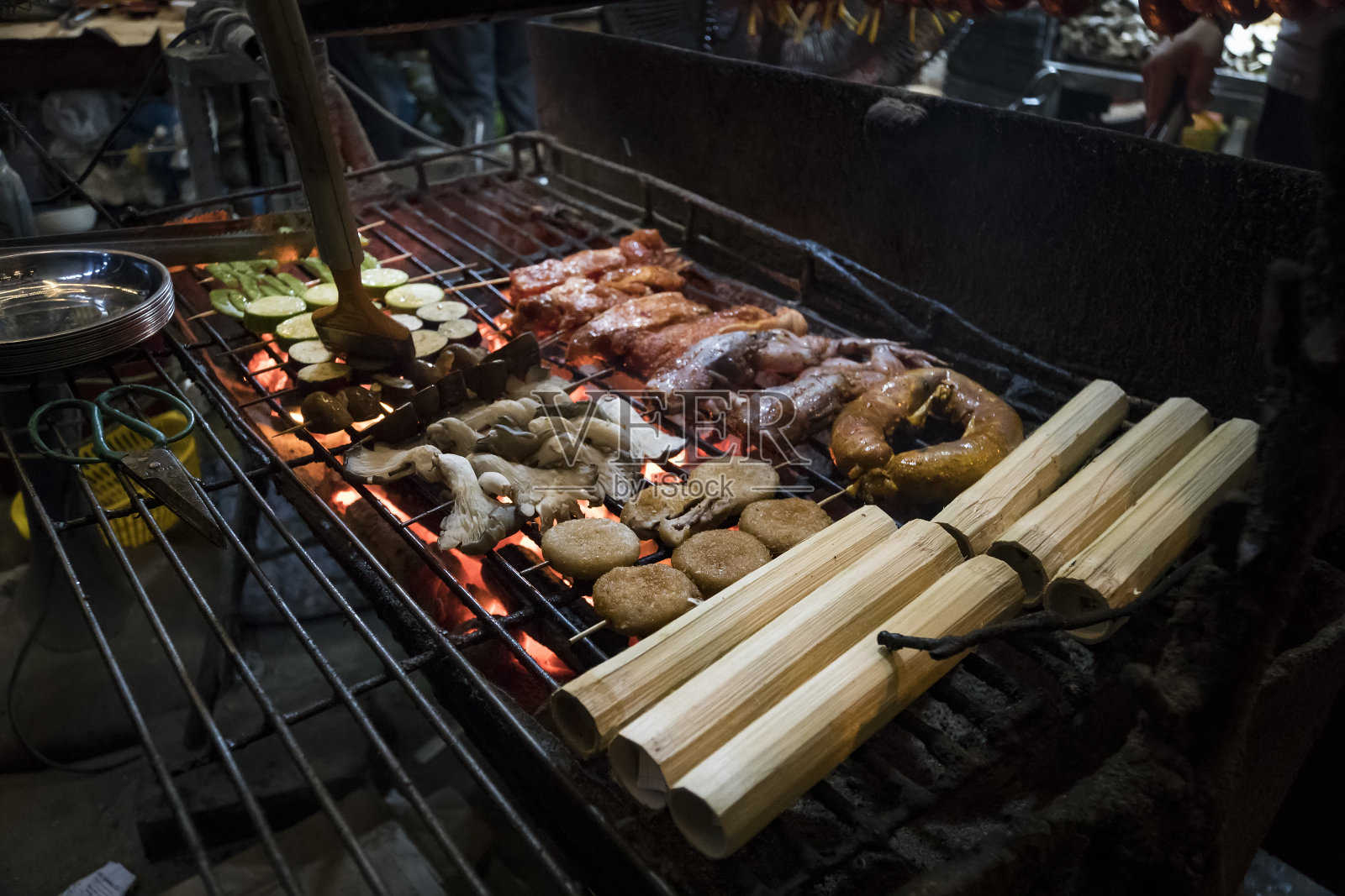 海鲜烤肉串，蔬菜，肉，米饭，竹子烤在户外晚上在越南的街道上照片摄影图片
