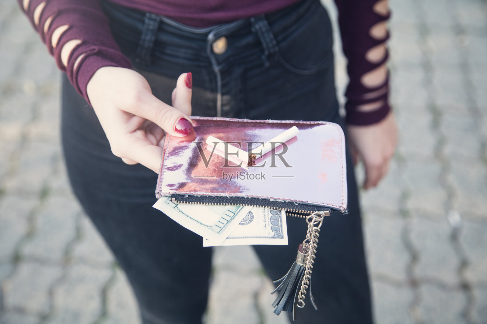 在户外拿着钱和钱包的女人。照片摄影图片