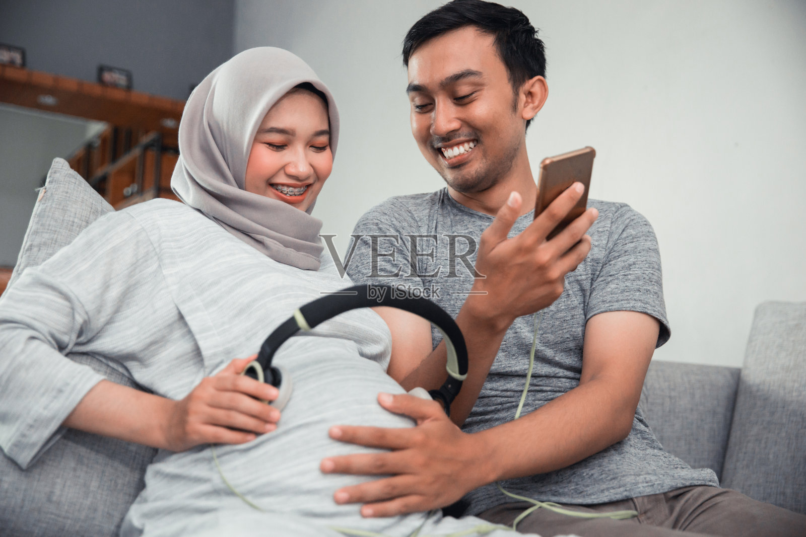 肚子上放着耳机的孕妇照片摄影图片