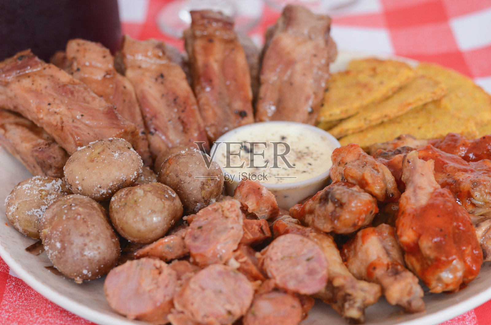 一盘排骨，鸡翅，香肠配玉米片和酱汁。照片摄影图片