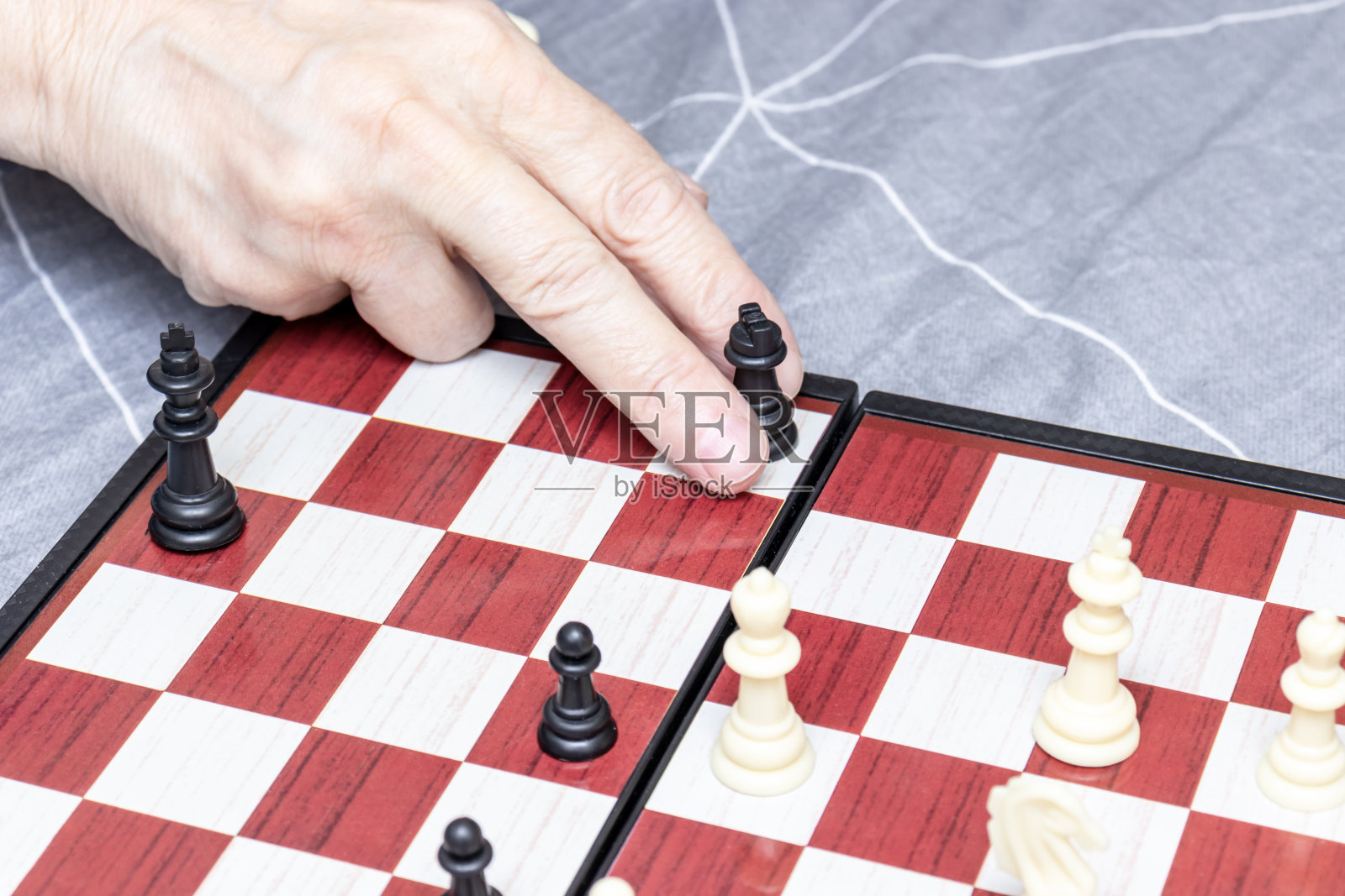 一名老年妇女的手近距离下棋，为退休人员娱乐和智力活动的概念照片摄影图片