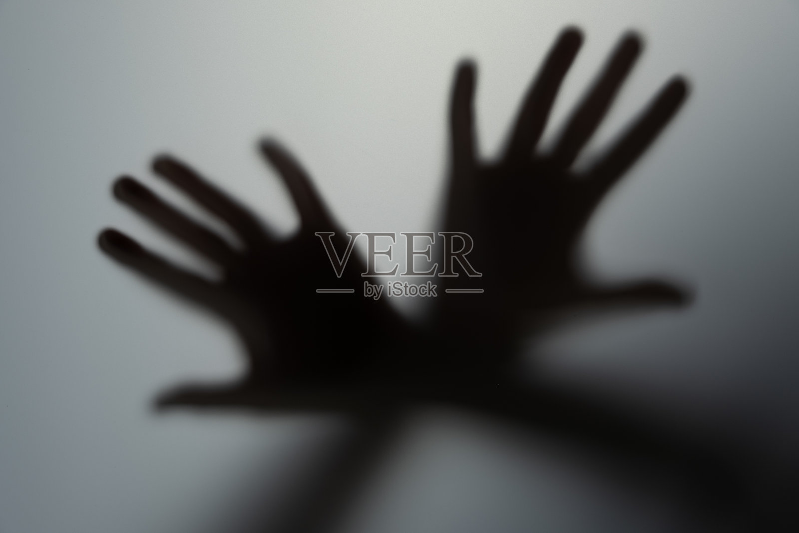 磨砂玻璃后面那个男人的影子手。模糊的手抽象万圣节，一个模糊的手的剪影模糊的影子玻璃后面的手。照片摄影图片