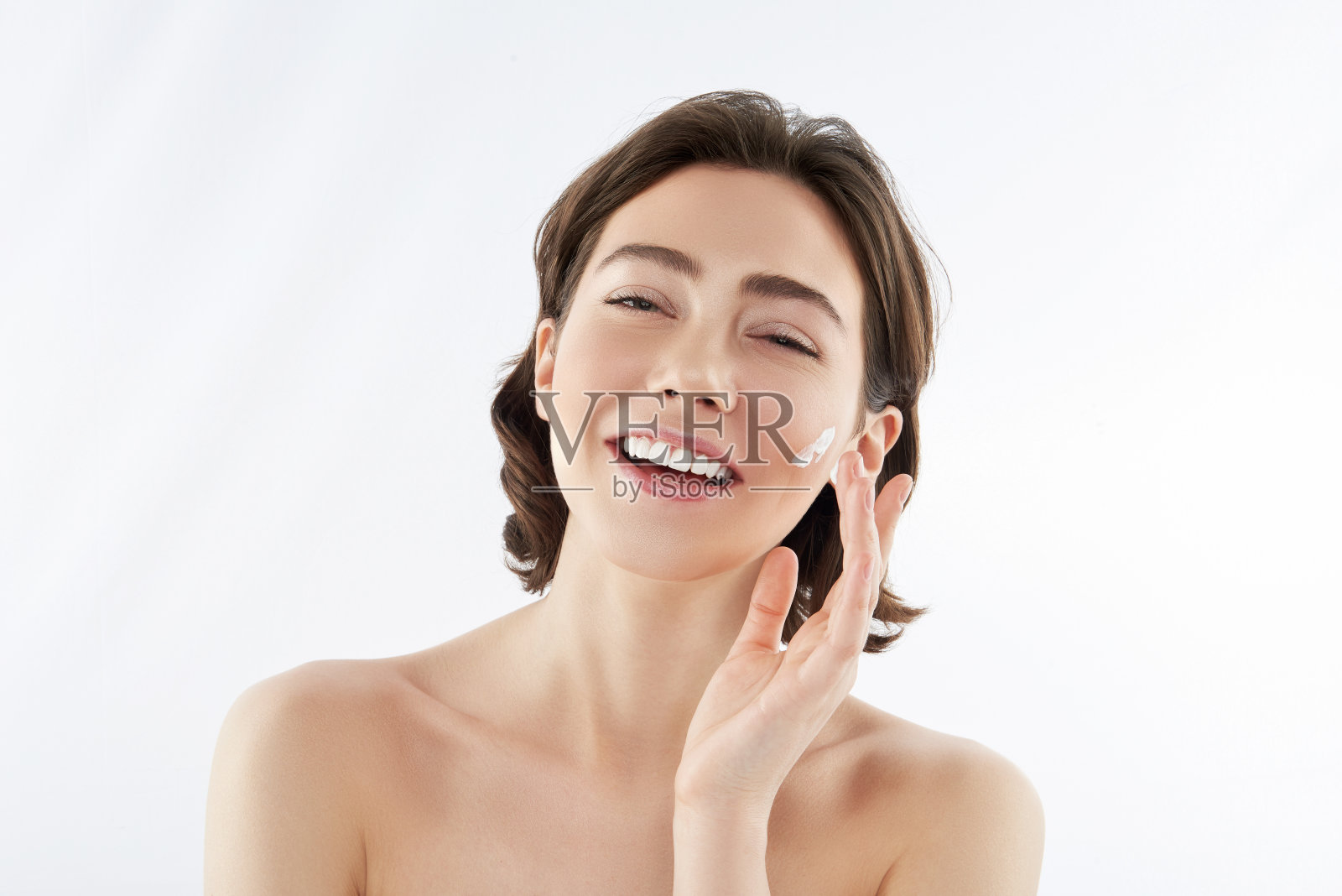 快乐的漂亮女人在脸上擦面霜照片摄影图片