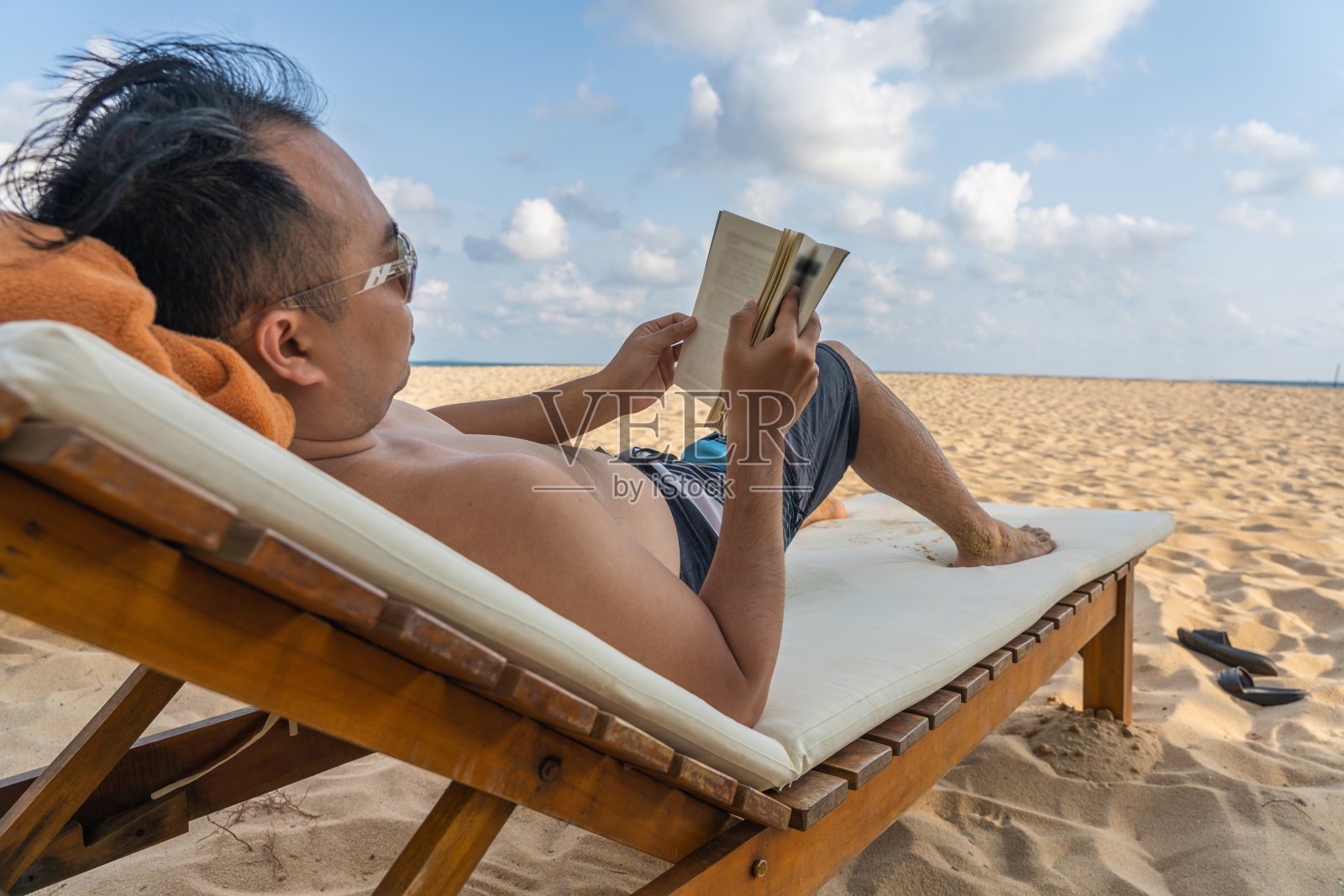 男人在海滩上放松，看书照片摄影图片