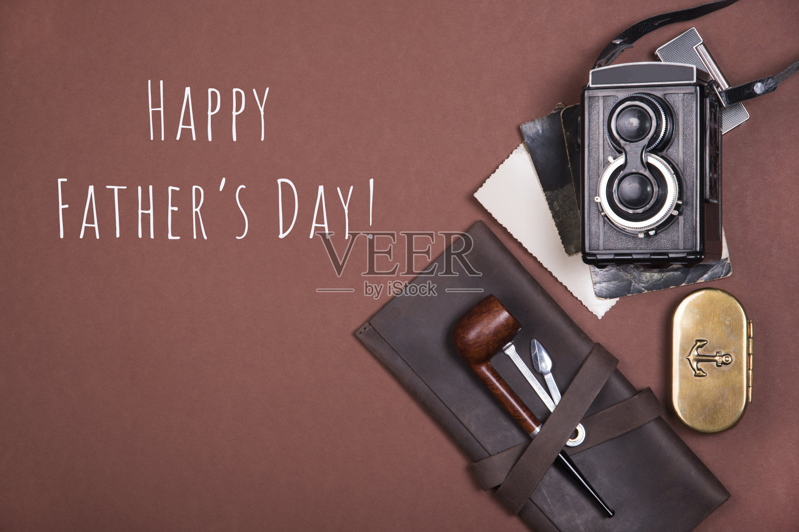 由一个棕色皮箱上的烟斗、烟草配件、旧相机和老式照片组成。前视图。照片摄影图片