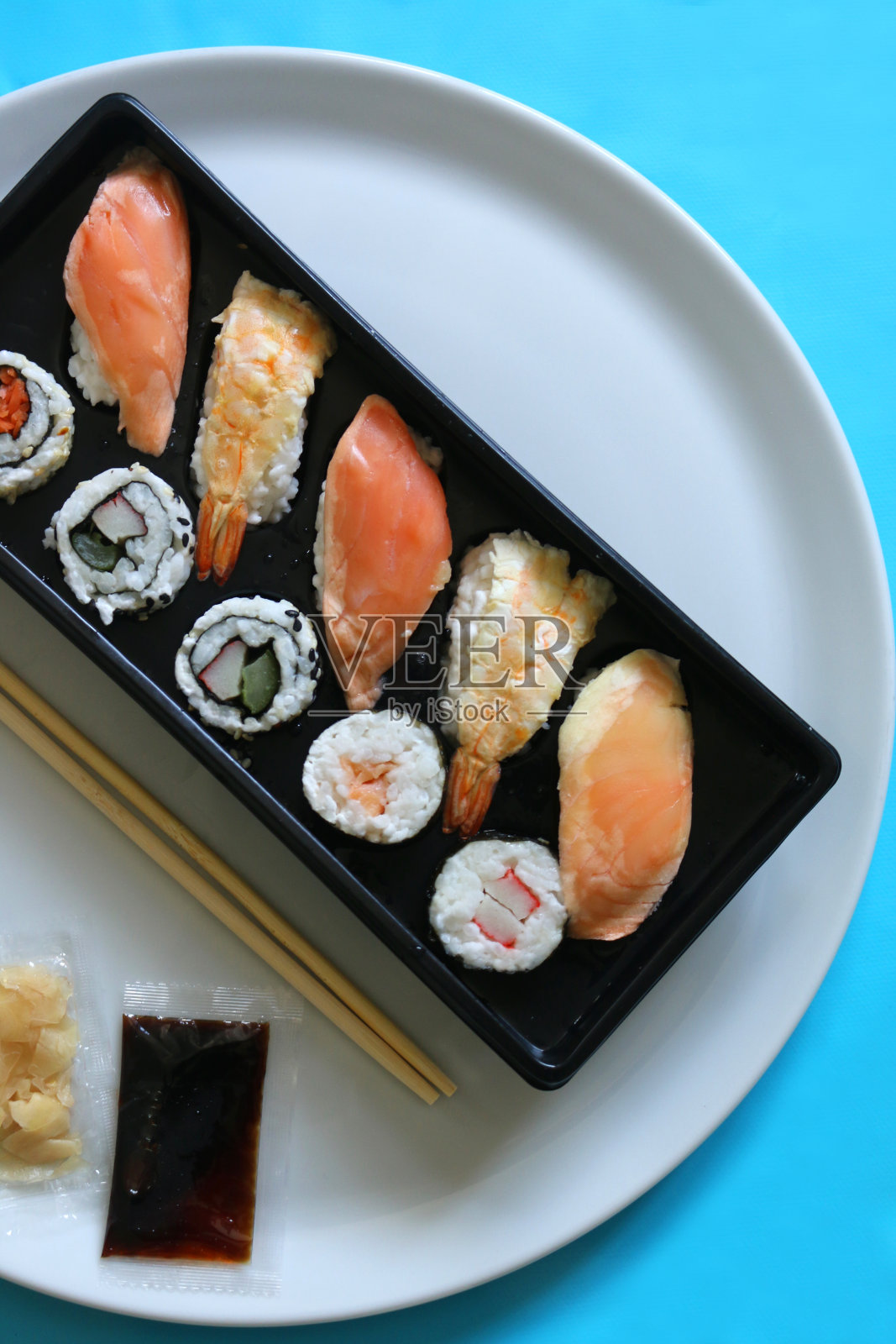 日本餐厅寿司盘的形象，新鲜准备的海鲜，日本寿司的类型- makizushi，细卷寿司/真卷寿司，futomaki，浦卷寿司，手握寿司，粗卷寿司，生鱼片，新鲜鲑鱼，金枪鱼，虾尾，对虾，糯米饭，海藻皮照片摄影图片