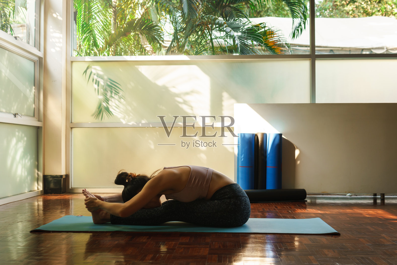 年轻的亚洲妇女准备瑜伽训练，通过伸展和腿非常灵活的身体反射在窗口照片摄影图片