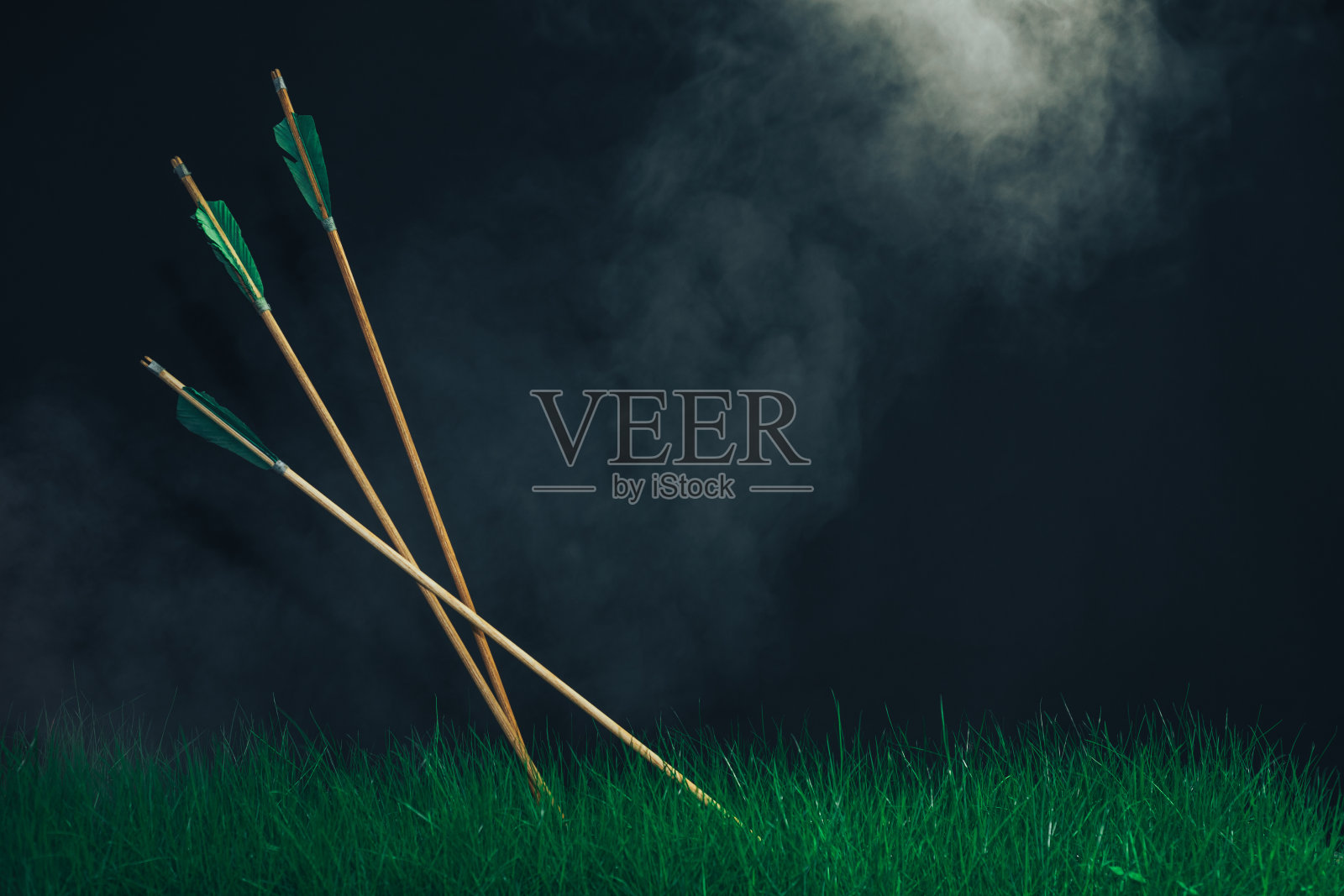 草丛中有三支木箭。美丽的烟雾的背景。中世纪的武器手工制作的。照片摄影图片