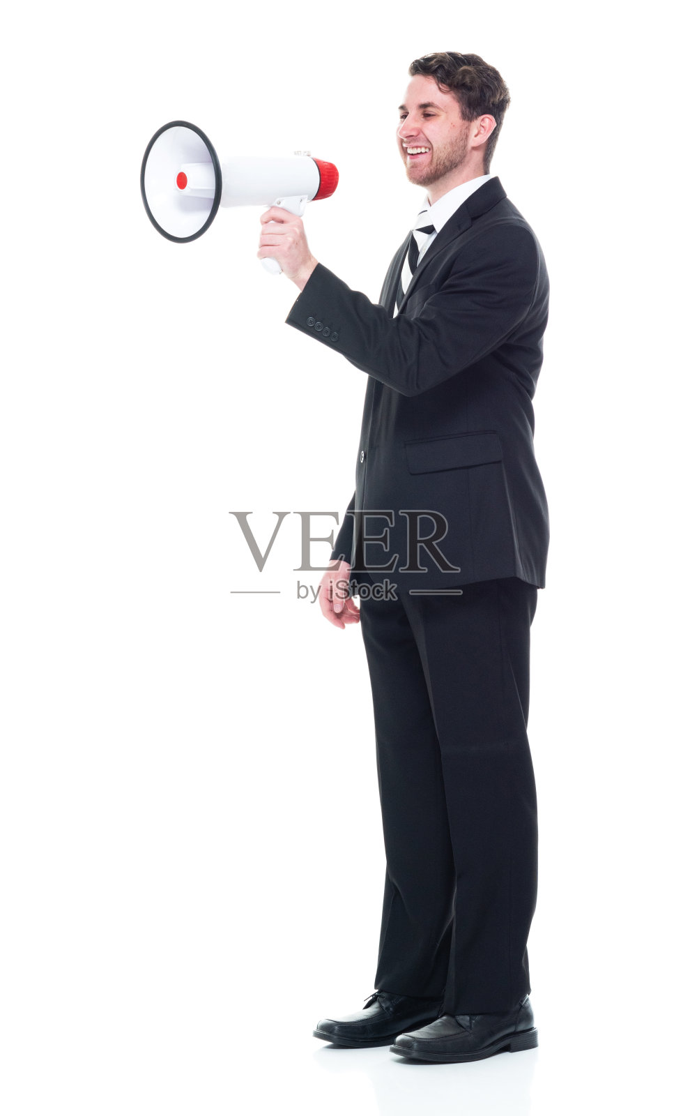 年轻英俊的商人穿着西装，打着领带，用着扩音器照片摄影图片