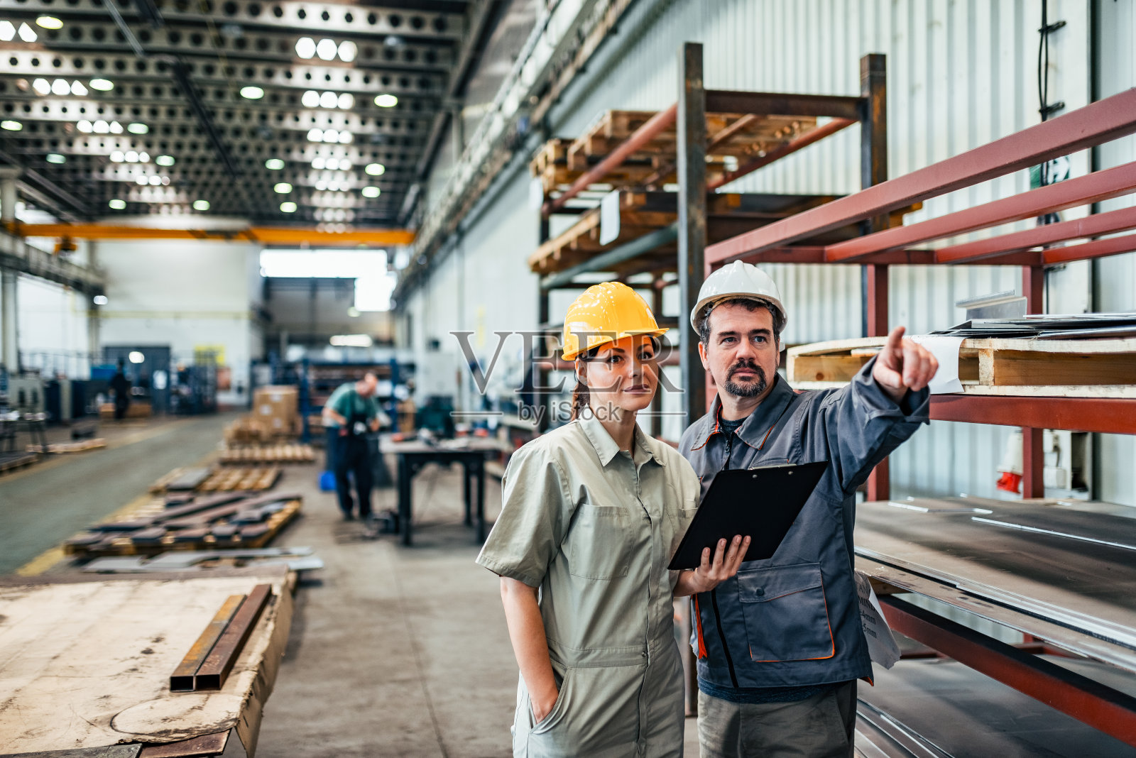 两名工程师，一男一女，在工厂里讨论。照片摄影图片