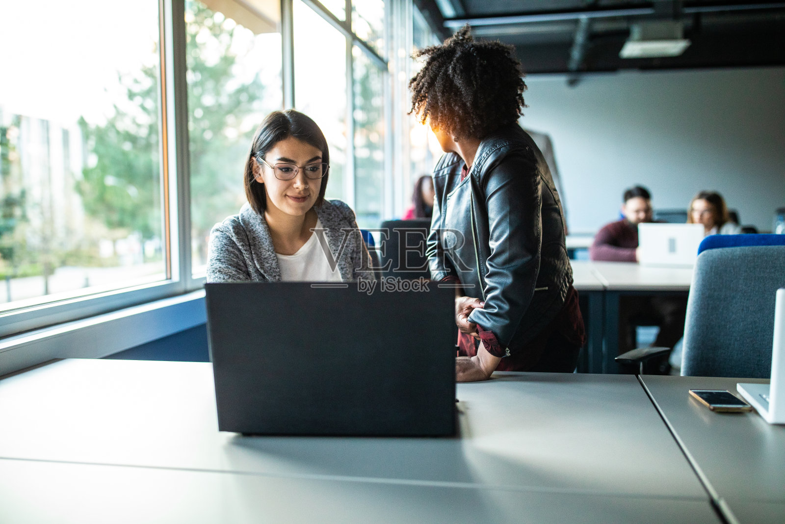 两位女性同事在办公室使用笔记本电脑照片摄影图片